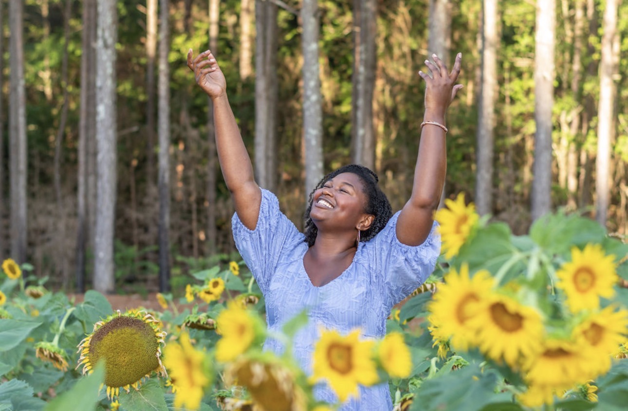 Precious Neely with arms lifted in praise among sunflowers