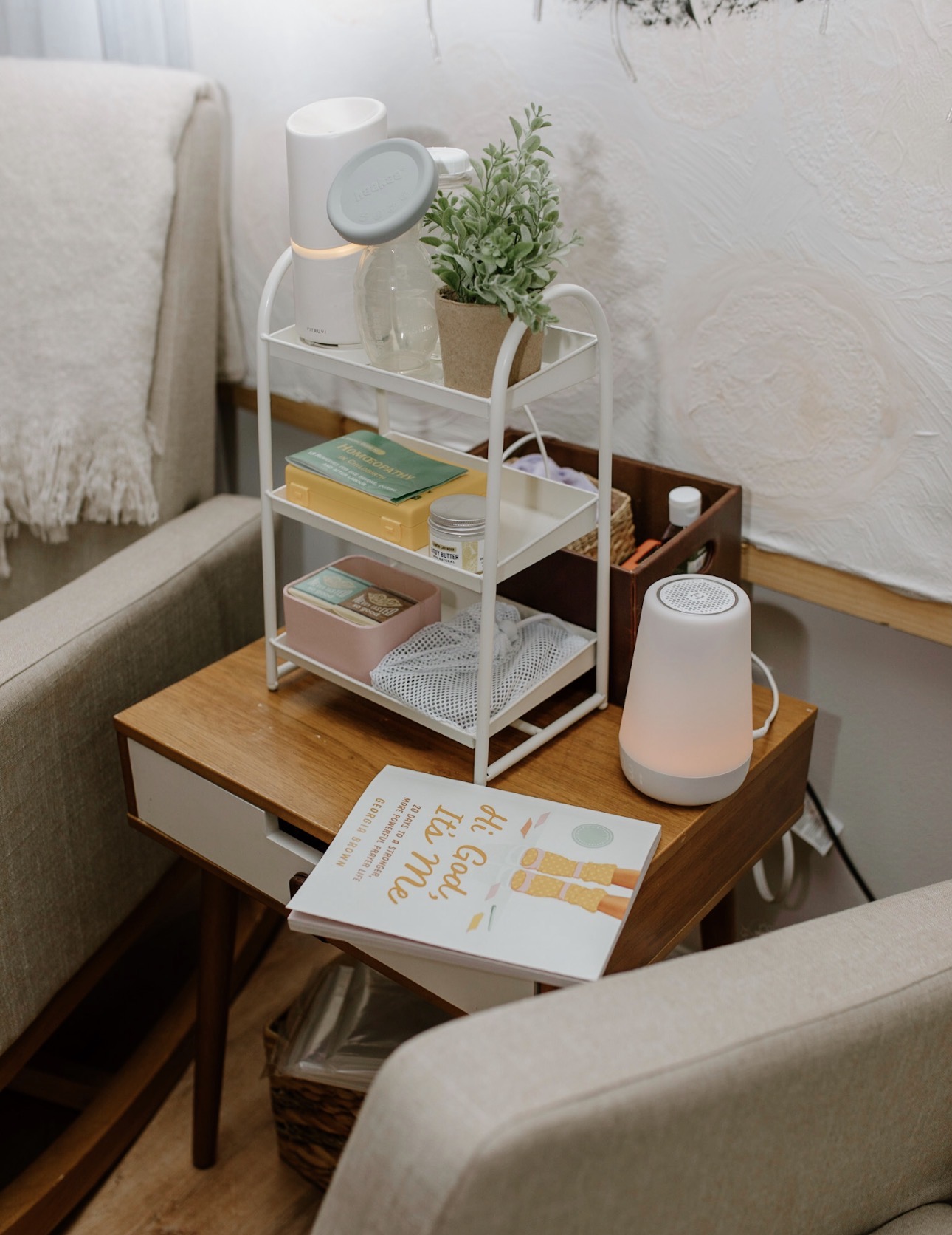 A prepared postpartum care station with a diffuser, books, and comforts