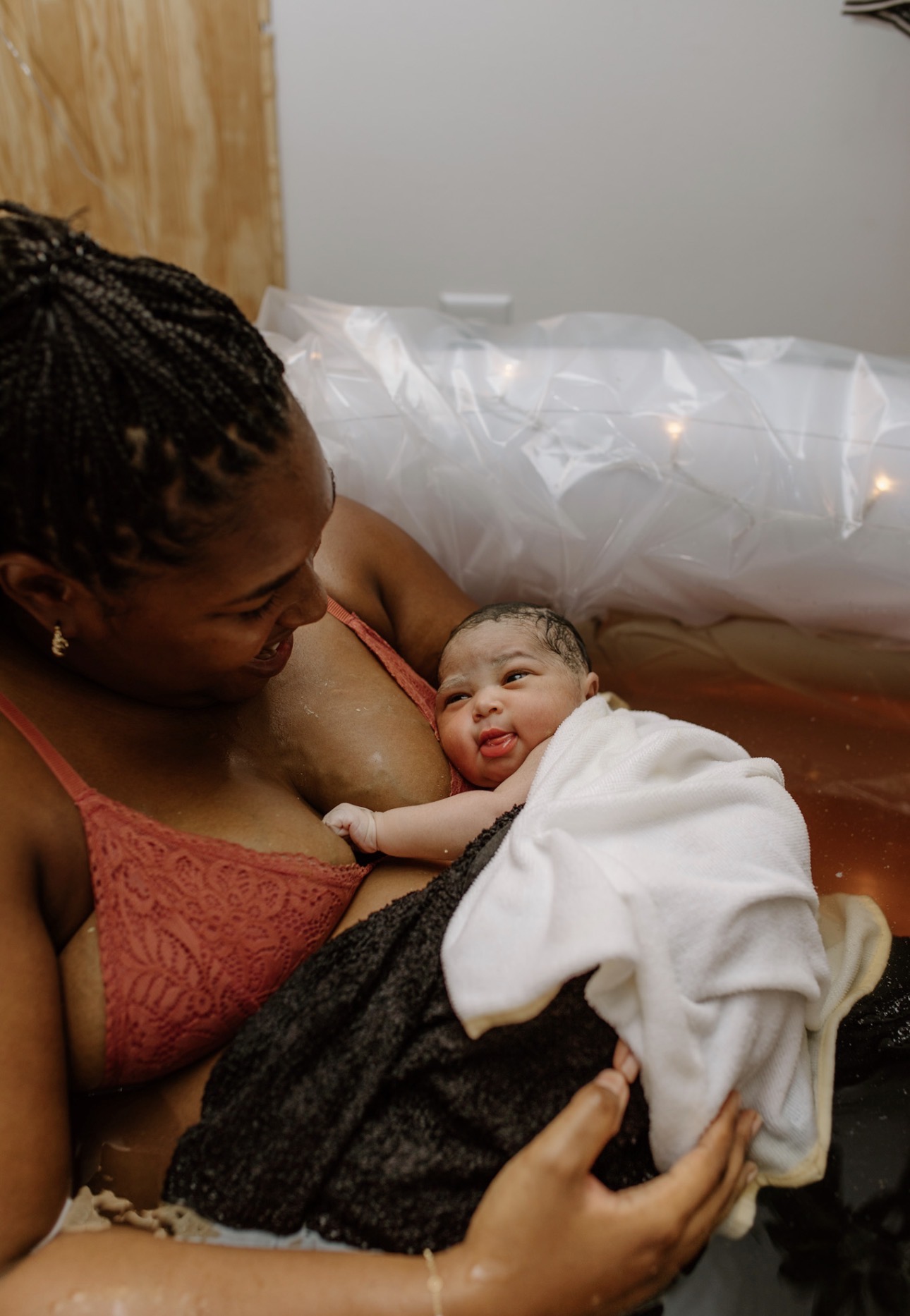 Precious holding her newborn baby in the birth pool, both smiling